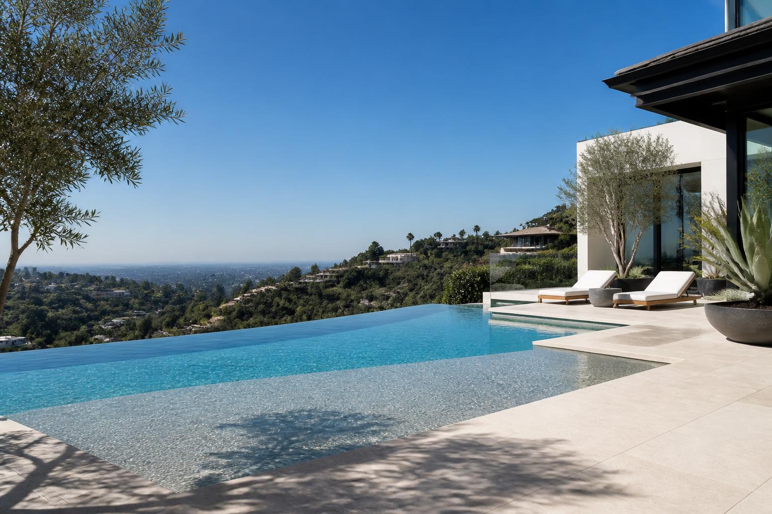 Illustrative design inspiration: hillside modern in-ground infinity pool with sun shelf, limestone deck, glass rail and drought-tolerant landscaping in late-morning light